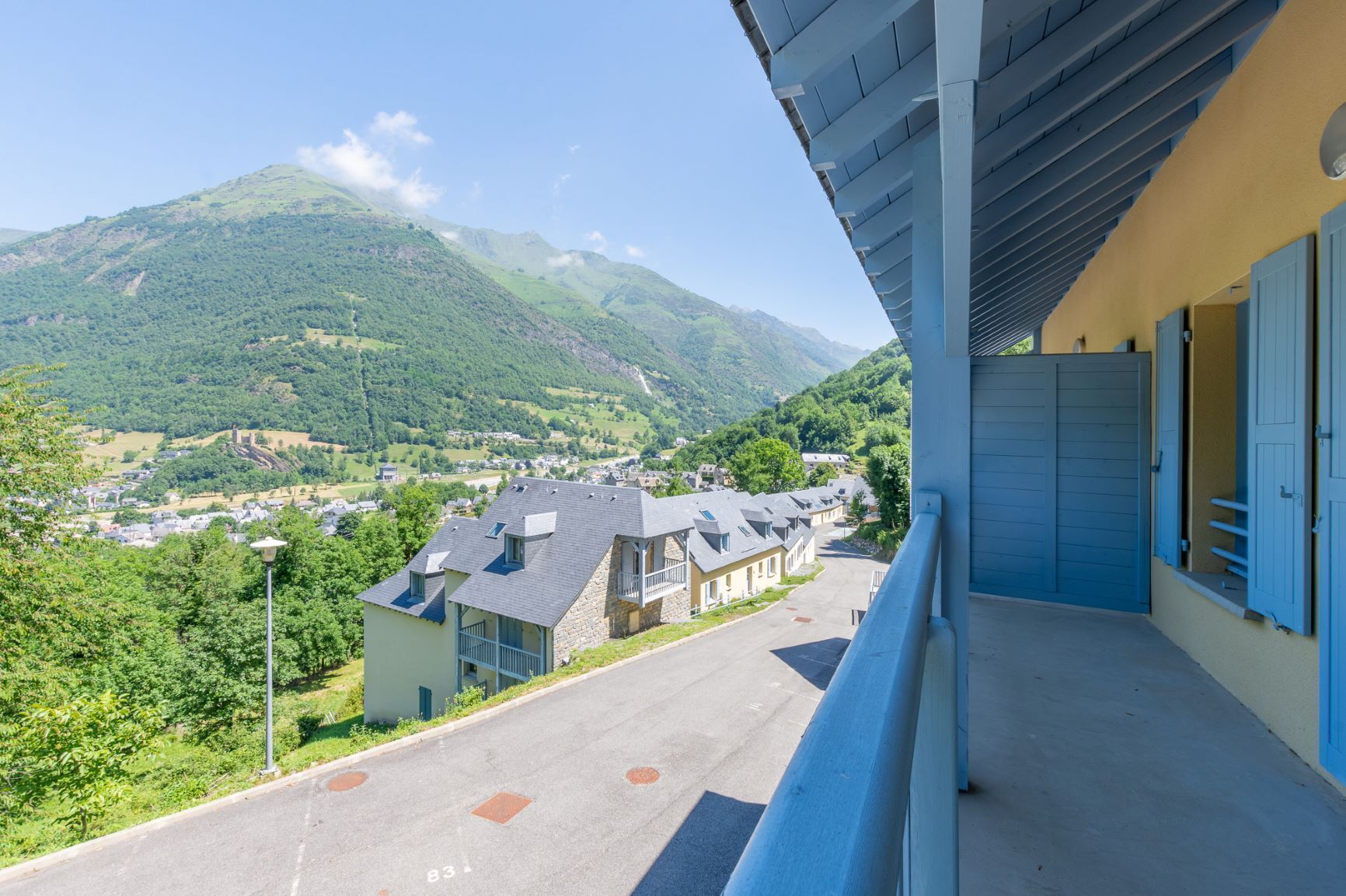 A balcony with a view of a mountain and a village below.