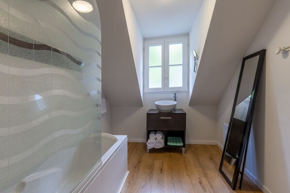 A modern bathroom with a freestanding bathtub, a white sink, and a mirror.