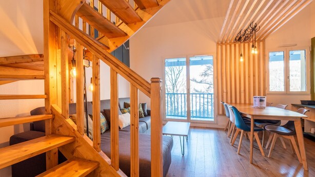 A wooden staircase leading to a balcony with a view, a dining area with chairs and a table, and a cozy seating area with cushions. - Résidence Les Balcons de l'Yse (Luz-Saint-Sauveur)