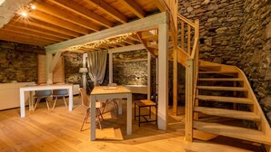 A rustic wooden interior with a stone wall, a wooden staircase, and a dining area with chairs and a table. - Résidence Les Balcons de l'Yse (Luz-Saint-Sauveur)