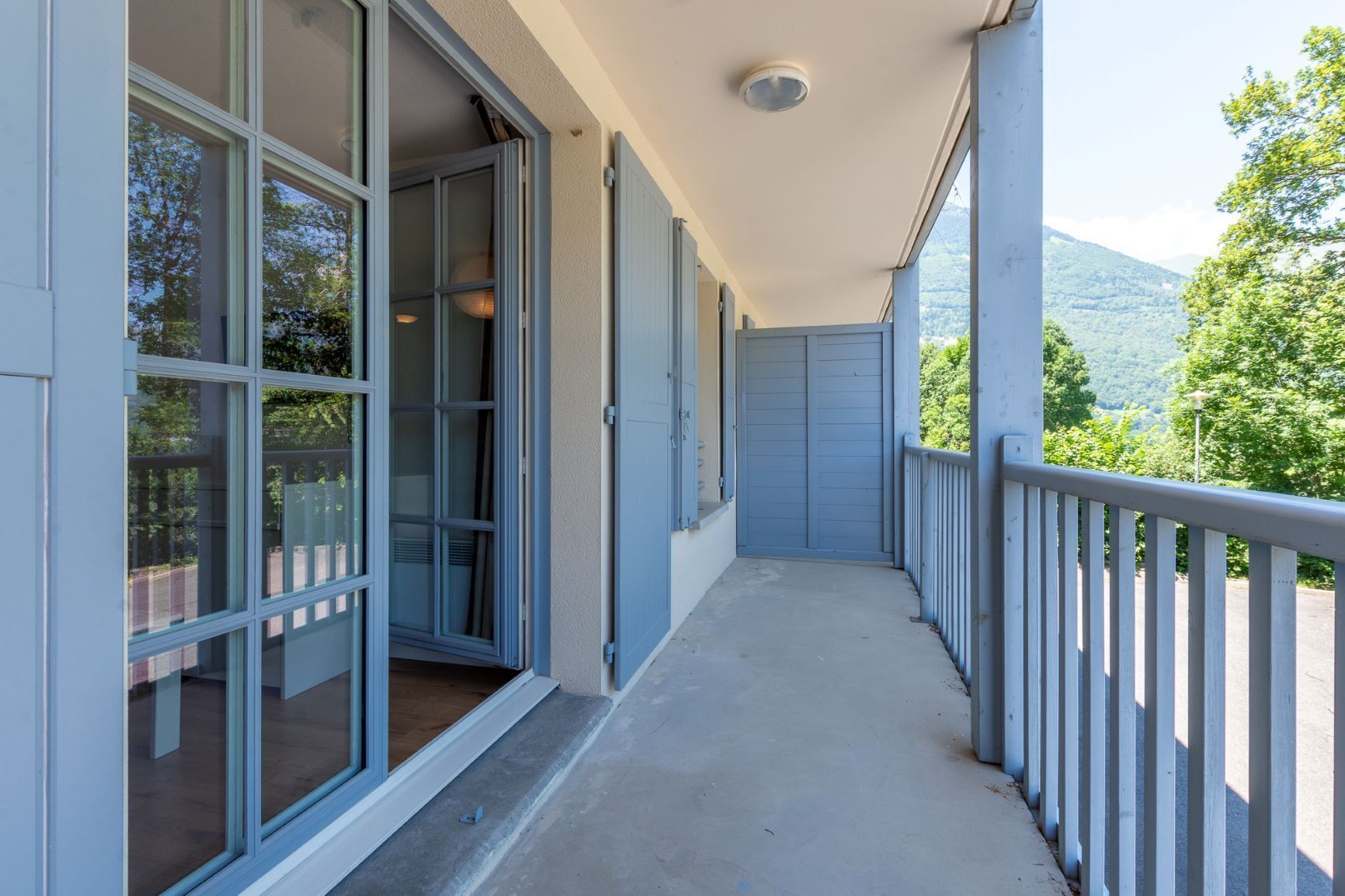 A covered balcony with a view of a mountainous landscape.