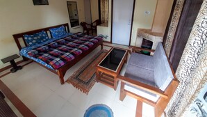 A room with a bed, a small table, a chair, and a sofa. - Janardan Resort Pangot (Kosiyakutoli)