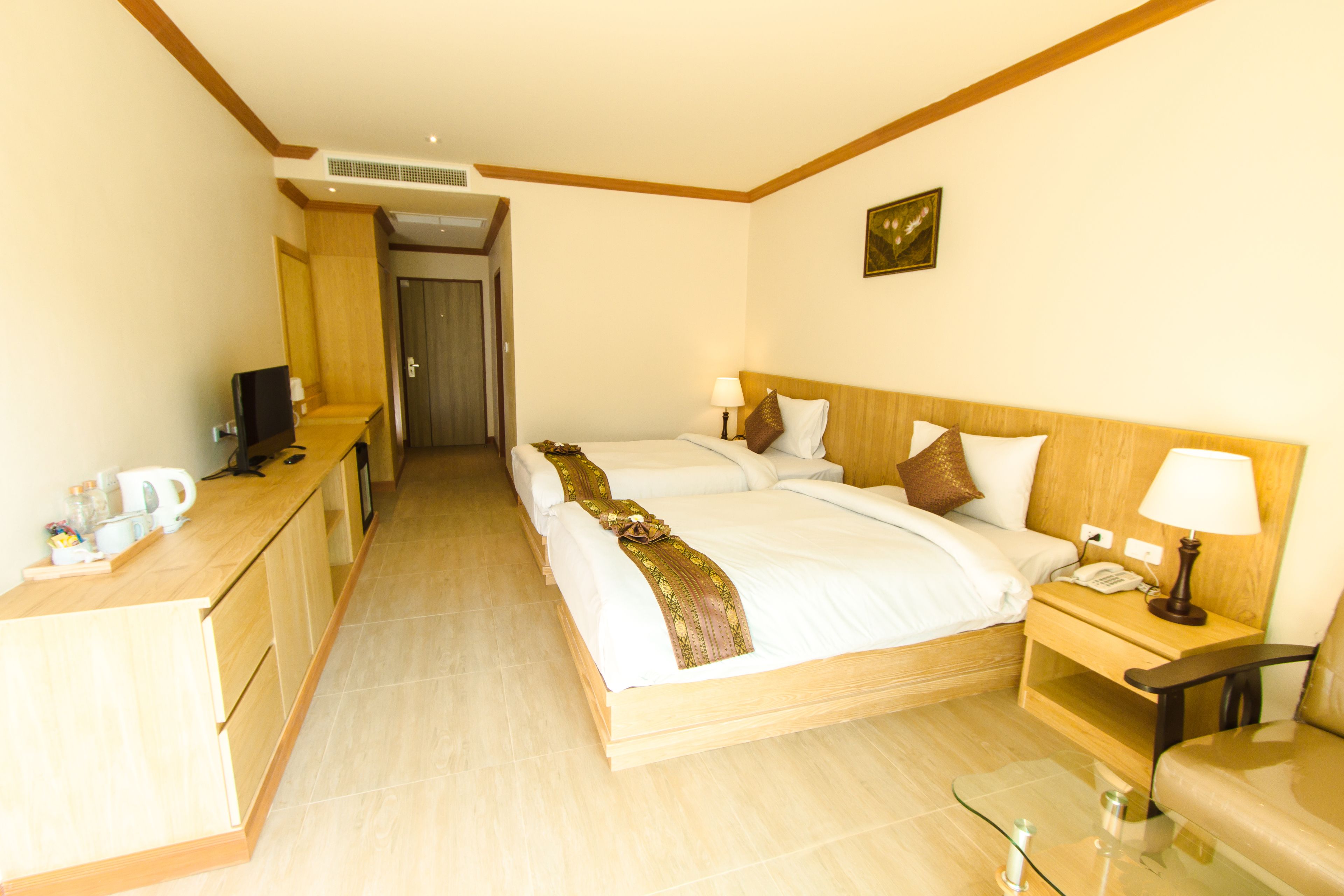 Une chambre d’hôtel avec deux lits, un bureau, une chaise, une table de chevet avec une lampe et un téléviseur.