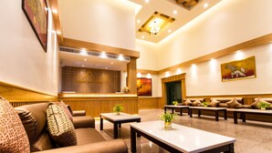 Un hall de hotel con mostrador de recepción, sofás y mesas.