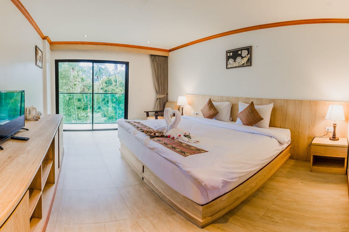 Une chambre d’hôtel avec un grand lit, une télévision, un bureau et une vue sur l’extérieur.