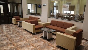 Un hall con arreglos de asientos, una mesa de recepción y un espejo grande que refleja el interior.