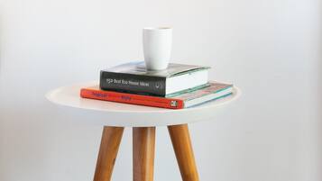 Ein Tisch mit einer Lampe, einer weißen Tasse und einem Bücherstapel.