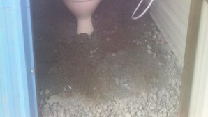 Un baño pequeño y cerrado con un inodoro y un tanque de agua.