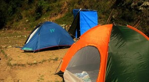 Three tents with different colors and designs, set up on a dirt ground with sparse vegetation in the background. - Janardan Resort Churaini - Campsite (Kosiyakutoli)