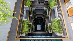 A modern building with a central staircase surrounded by greenery and a pool at the bottom. - Lahome Boutique Villa and Apartment (Da Nang)