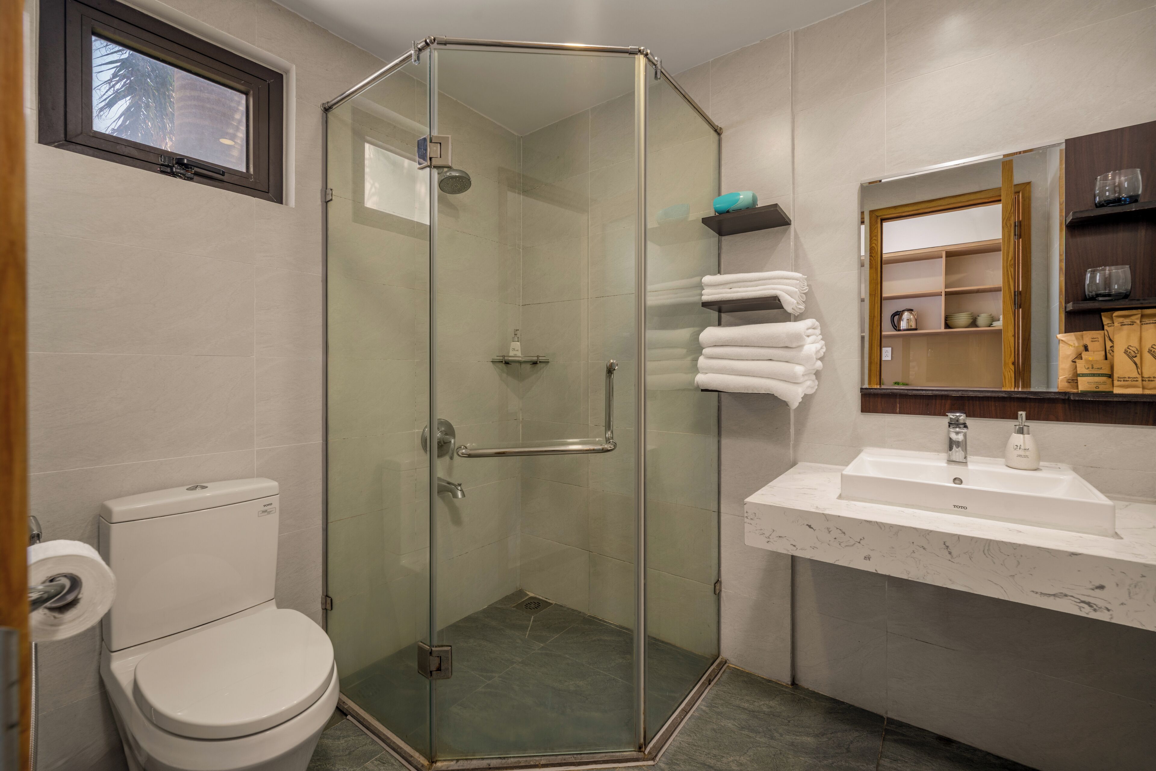 A modern bathroom with a glass-enclosed shower, a white toilet, and a marble sink.