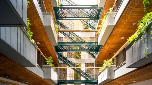 A multi-level atrium with a central staircase, surrounded by balconies with plants. - Lahome Boutique Villa and Apartment (Da Nang)