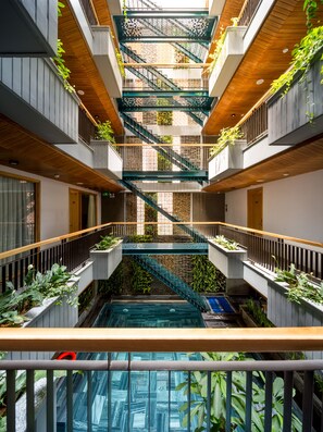 A multi-level atrium with a central staircase, surrounded by balconies with plants. - Lahome Boutique Villa and Apartment (Da Nang)