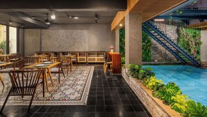 A restaurant with a pool area, including tables, chairs, and a staircase leading to a balcony. - Lahome Boutique Villa and Apartment (Da Nang)