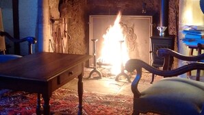 Una habitación con chimenea, una mesa de madera y una silla.