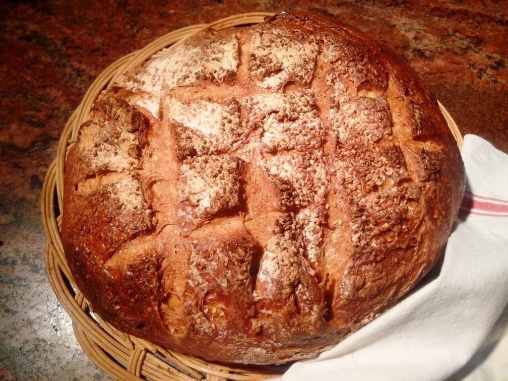 Un pain rond, à la croûte irrégulière, posé dans un panier tressé.