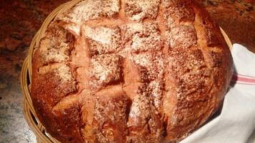 A round loaf of bread with a textured crust, placed in a woven basket.