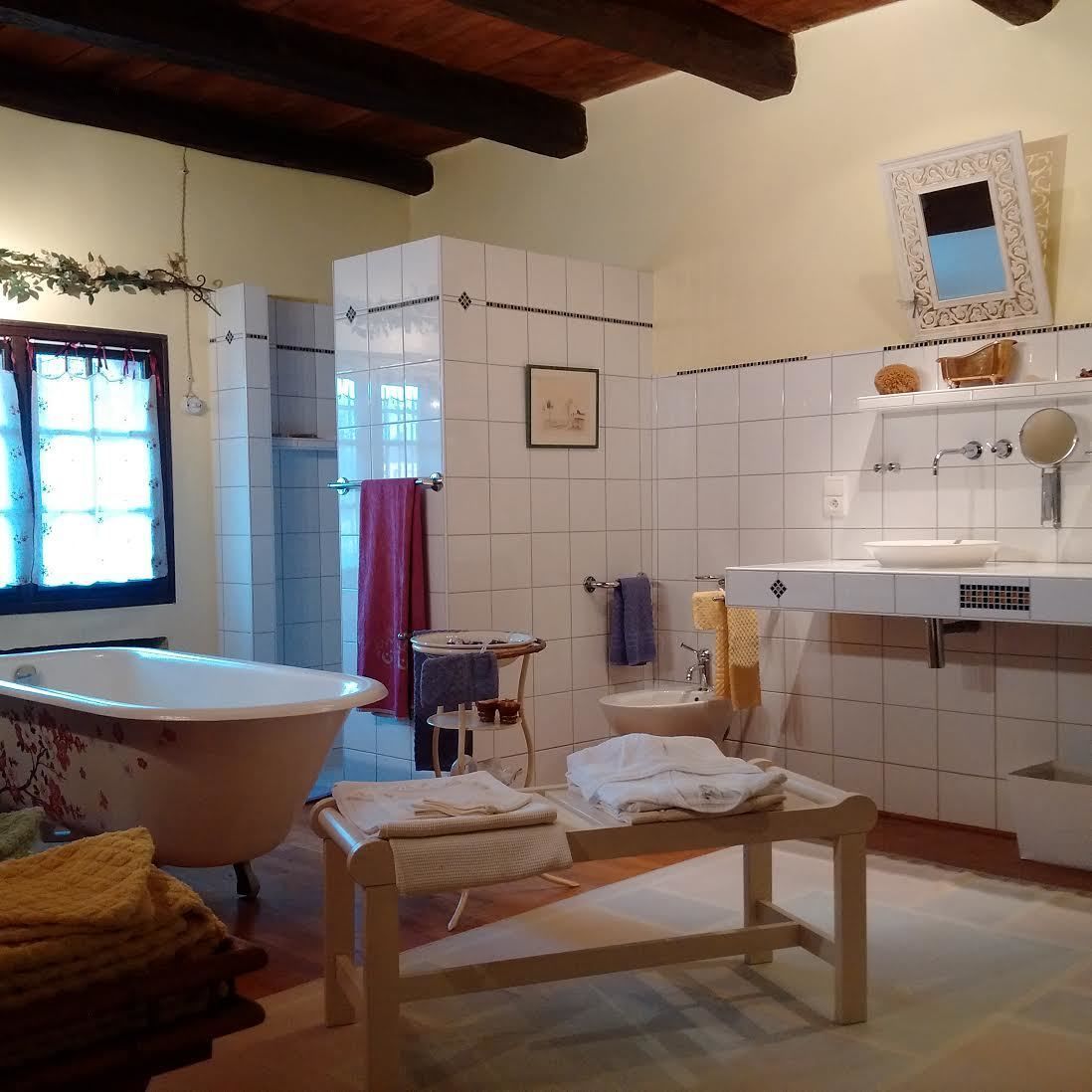 Un baño con una bañera independiente, un lavabo con espejo y un perchero para toallas.