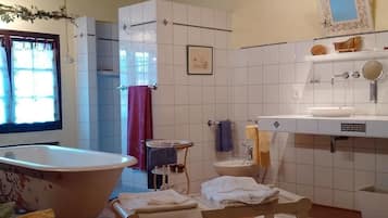 A bathroom with a freestanding bathtub, a sink with a mirror, and a towel rack.