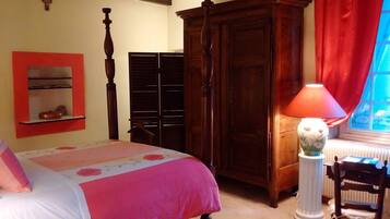 Ein Schlafzimmer mit einem Bett, einem Holzschrank, einem roten Vorhang und einer Tischlampe.
