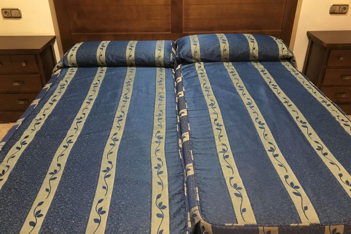A double bed with a blue and beige striped bedspread and matching pillows.