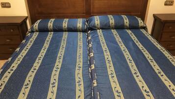 A double bed with a blue and beige striped bedspread and matching pillows.