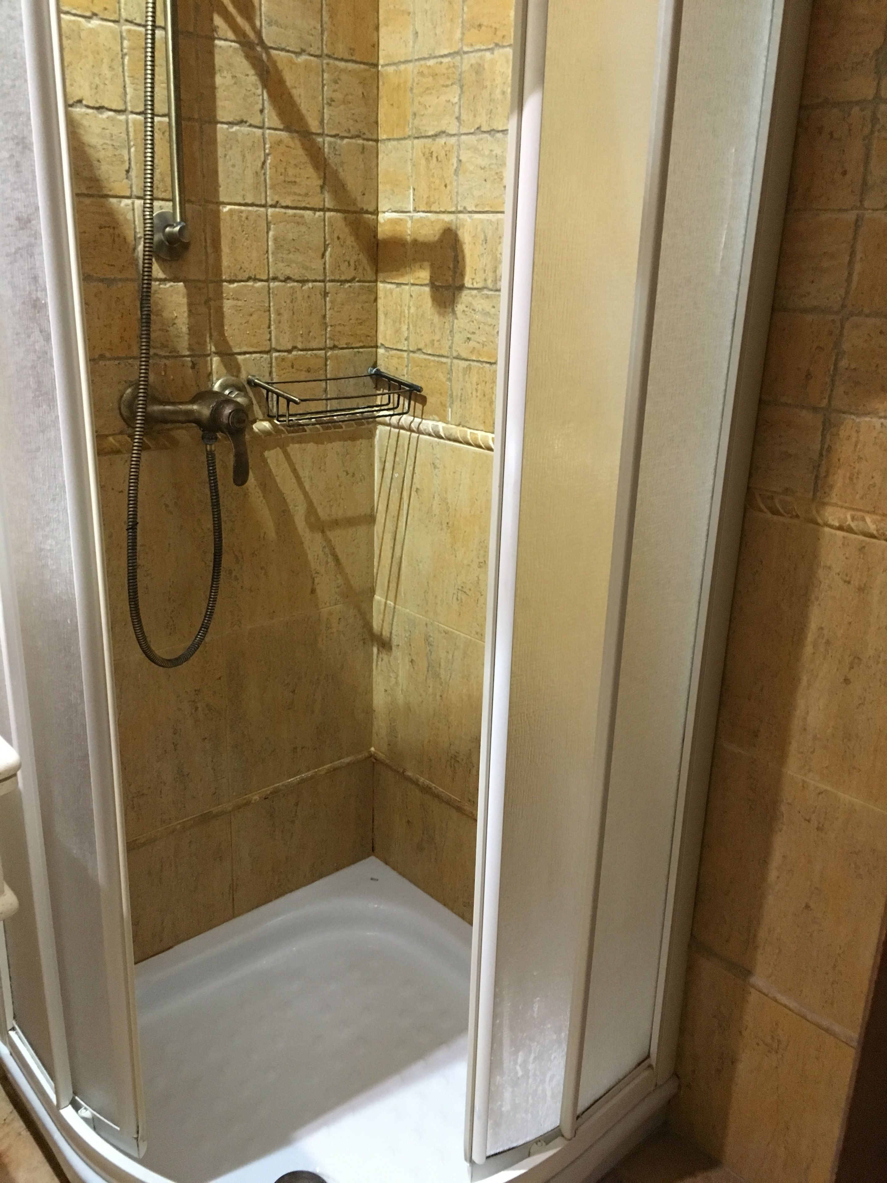 A shower with a glass door, a metal showerhead, and a towel rack.