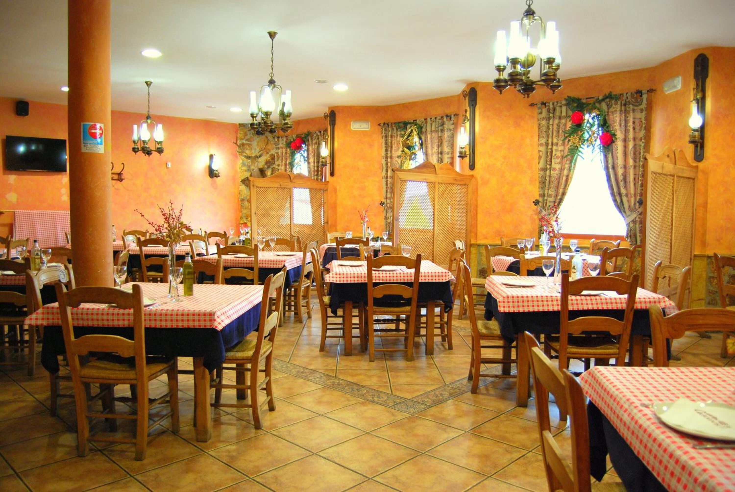 Un restaurante con varias mesas y sillas, sillas de madera y piso de baldosas.