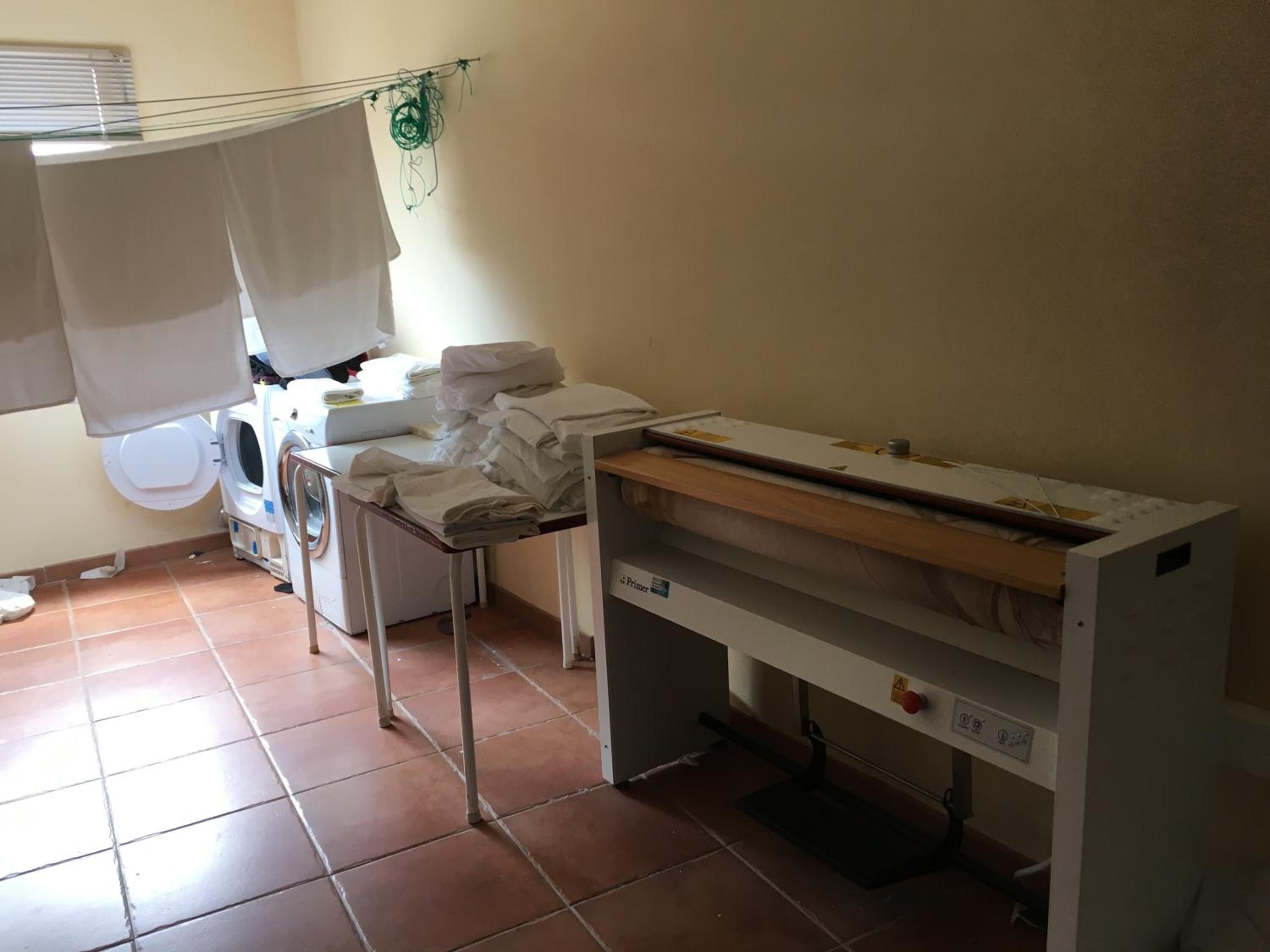 A laundry room with a washing machine, dryer, and ironing station.