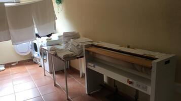 A laundry room with a washing machine, dryer, and ironing station.
