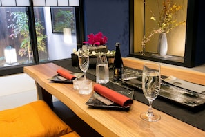 A dining table set with glasses, cutlery, and a vase with flowers.