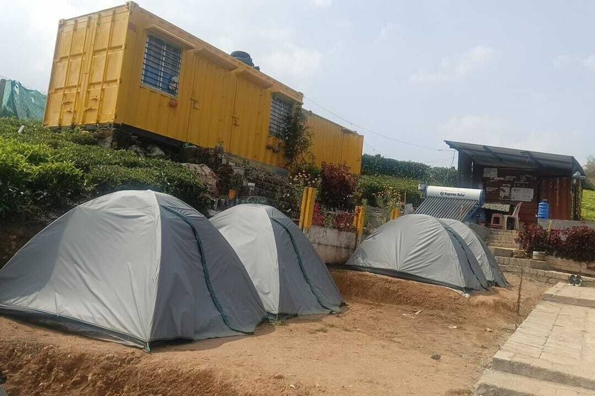 Un camping con varias tiendas de campaña y un edificio amarillo al fondo.