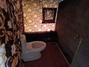 A bathroom with a toilet, a small window, and patterned wallpaper. - Janardan Tea Resort - Campsite (Kunda)