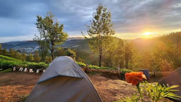 A tent set up in a natural landscape with a view of distant hills and a sunset. - Janardan Tea Resort - Campsite (Kunda)