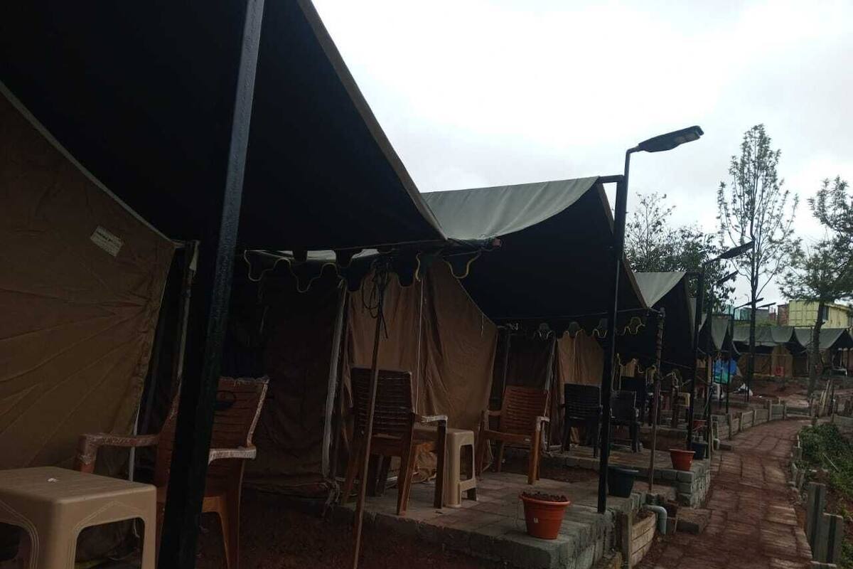 Un camping con tiendas de campaña, sillas y un sendero pavimentado.