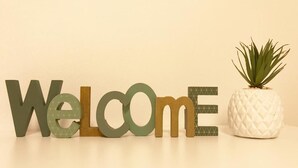 Large wooden letters spelling "Welcome" with a small potted plant beside them. - Manzoni Premium (Merano)