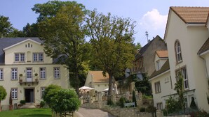 A traditional European-style building with a stone facade, a central entrance, and a small courtyard with a paved path. - Landhotel Schloss Sörgenloch (Sörgenloch)