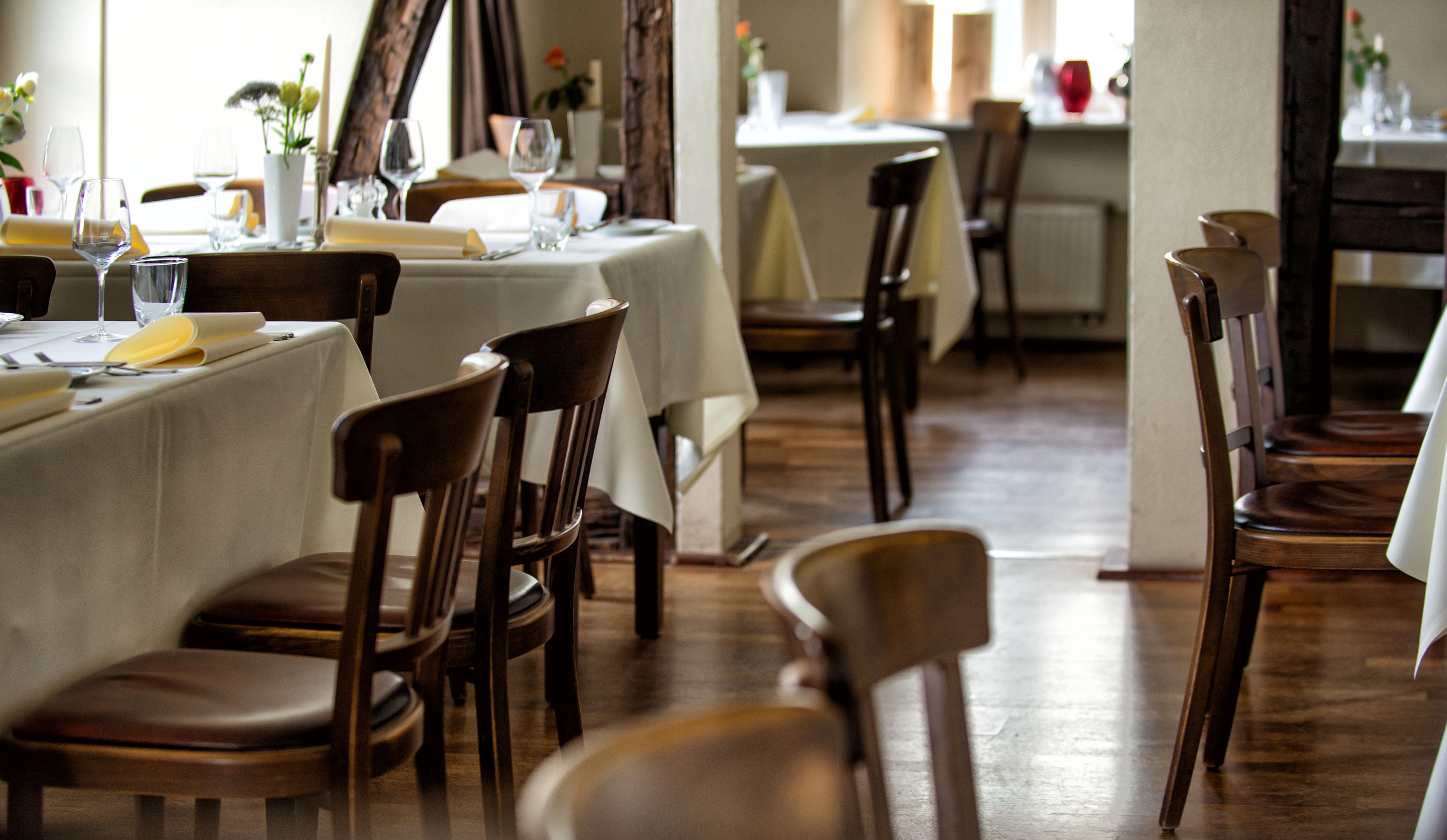 A restaurant with wooden chairs and tables, some with yellow napkins.