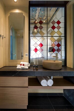 A modern bathroom with a large mirror, a round sink, and a decorative stained glass window. - Contessa Boutique Hotel (Chania)