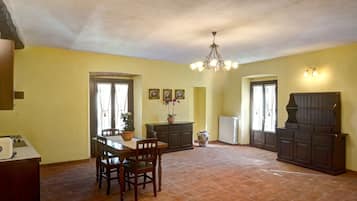 Uma cozinha espaçosa com mesa de jantar, cadeiras e um lustre.