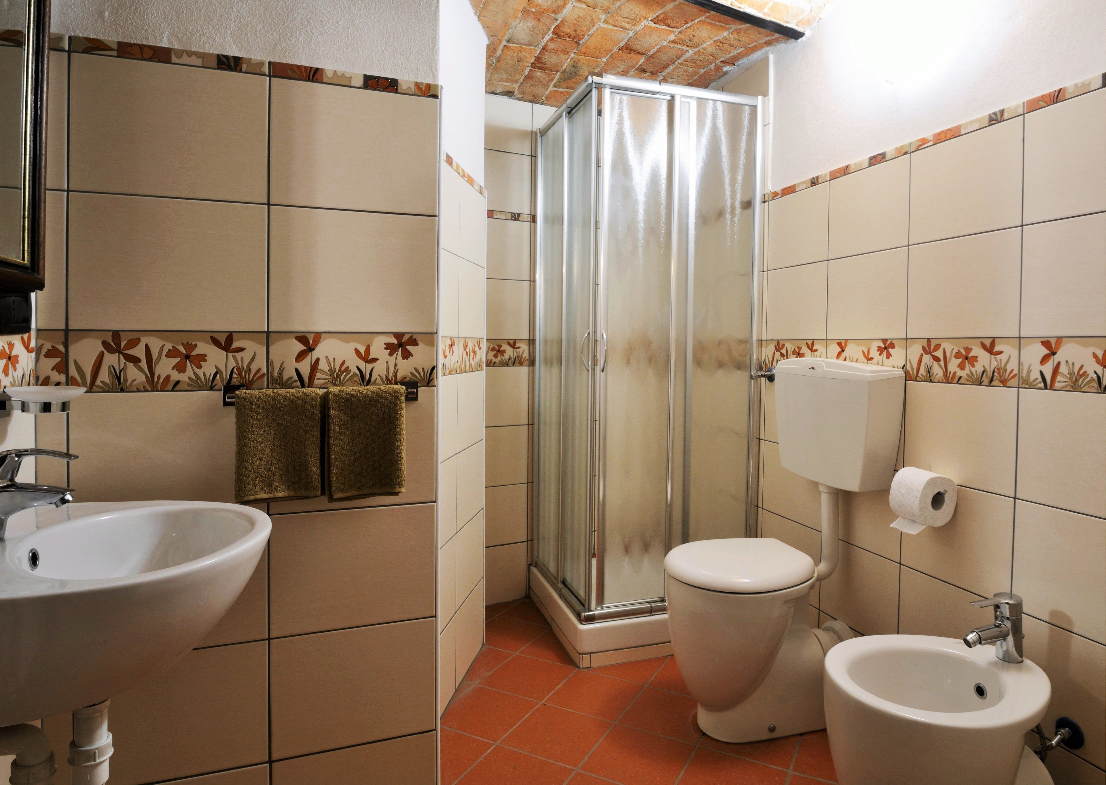 A bathroom with a sink, toilet, bidet, and shower.