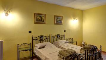 A room with two beds, a radiator, and wall-mounted light fixtures.