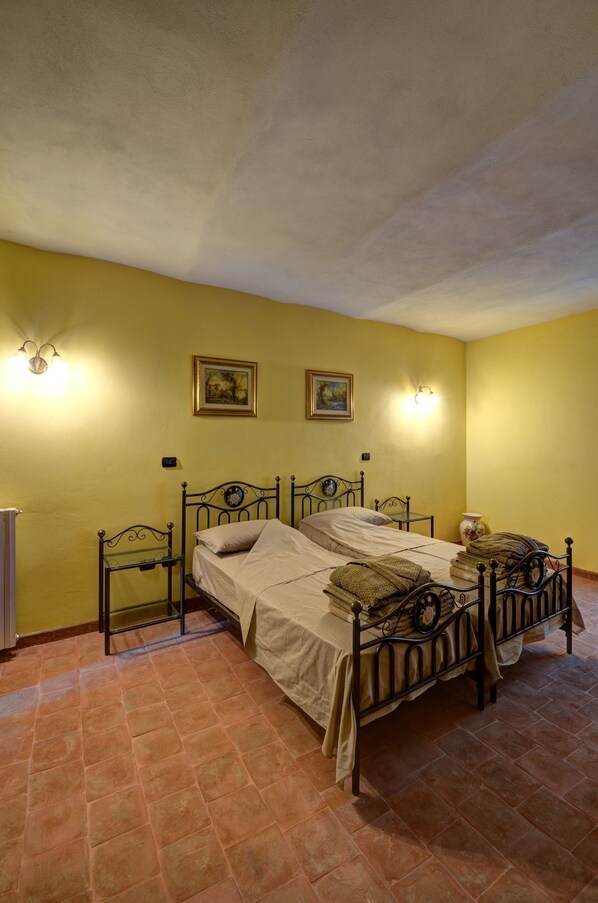 A room with two beds, a radiator, and wall-mounted light fixtures.