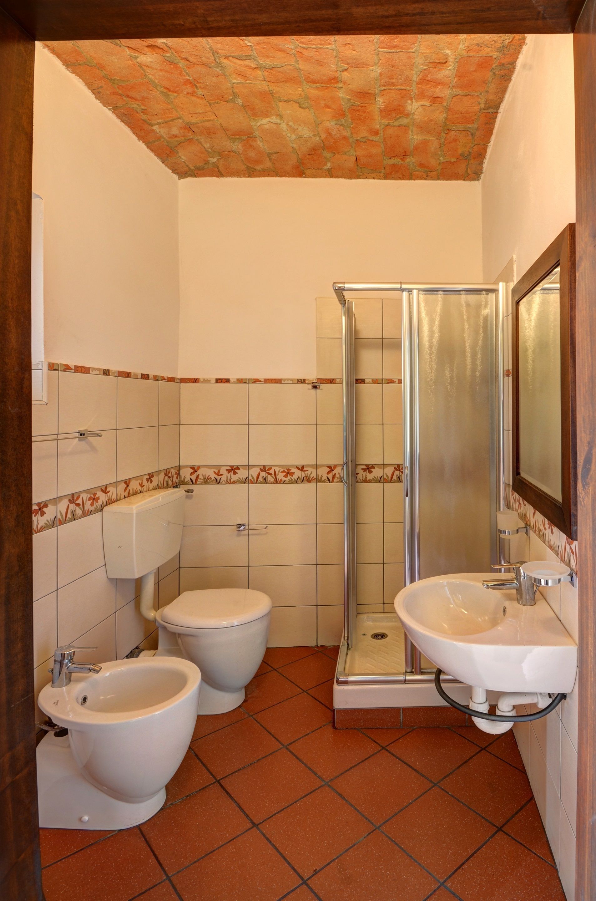 Un baño con ducha, dos inodoros, un bidé y un lavabo.