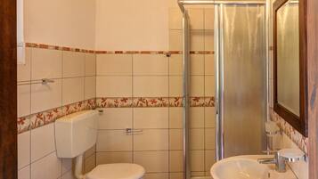 Un baño con ducha, dos inodoros, un bidé y un lavabo.