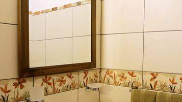 A bathroom with a white sink, a mirror, and floral-patterned tiles.