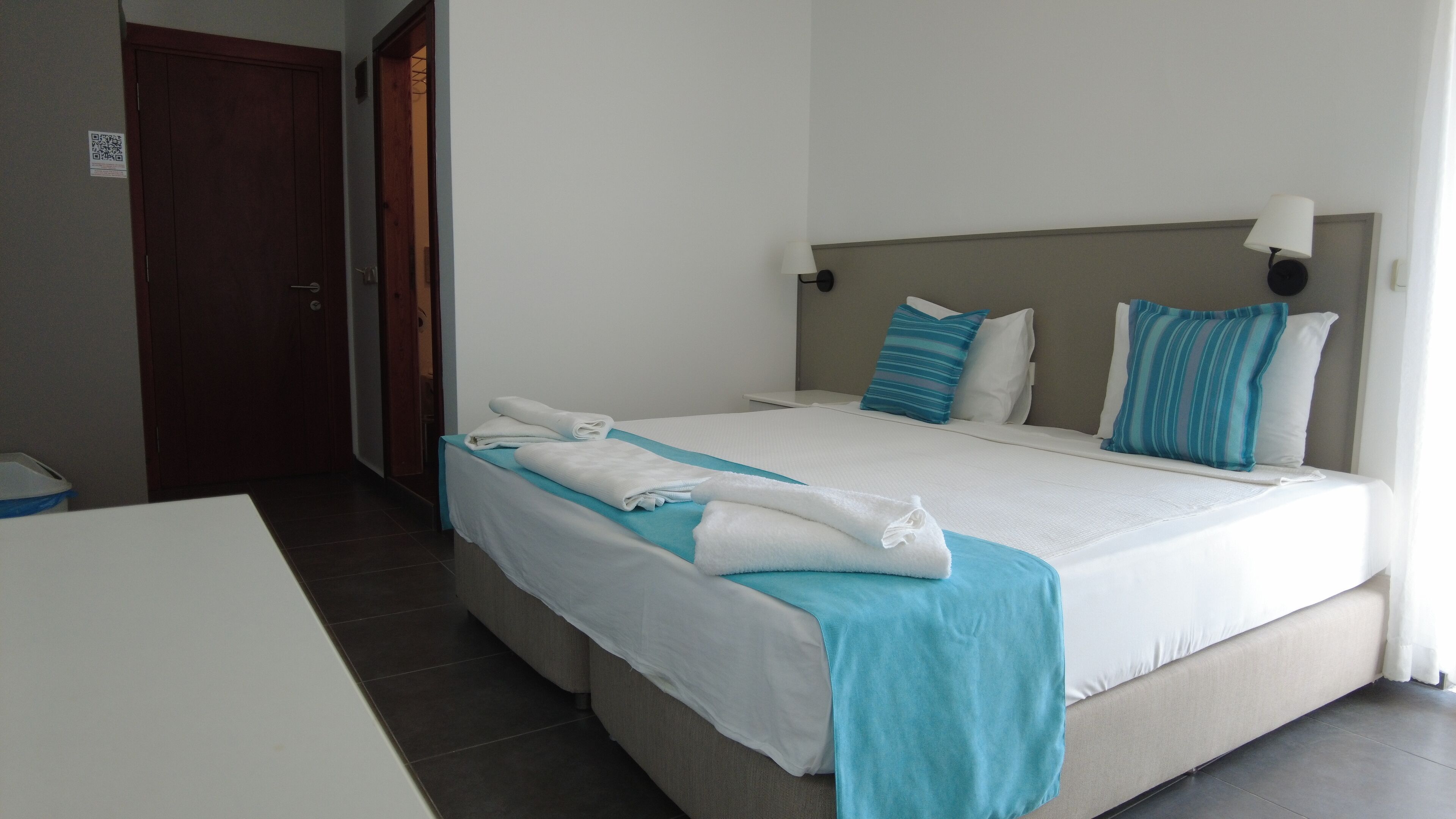 Une chambre d’hôtel avec un lit, une table de chevet, une lampe et une porte.