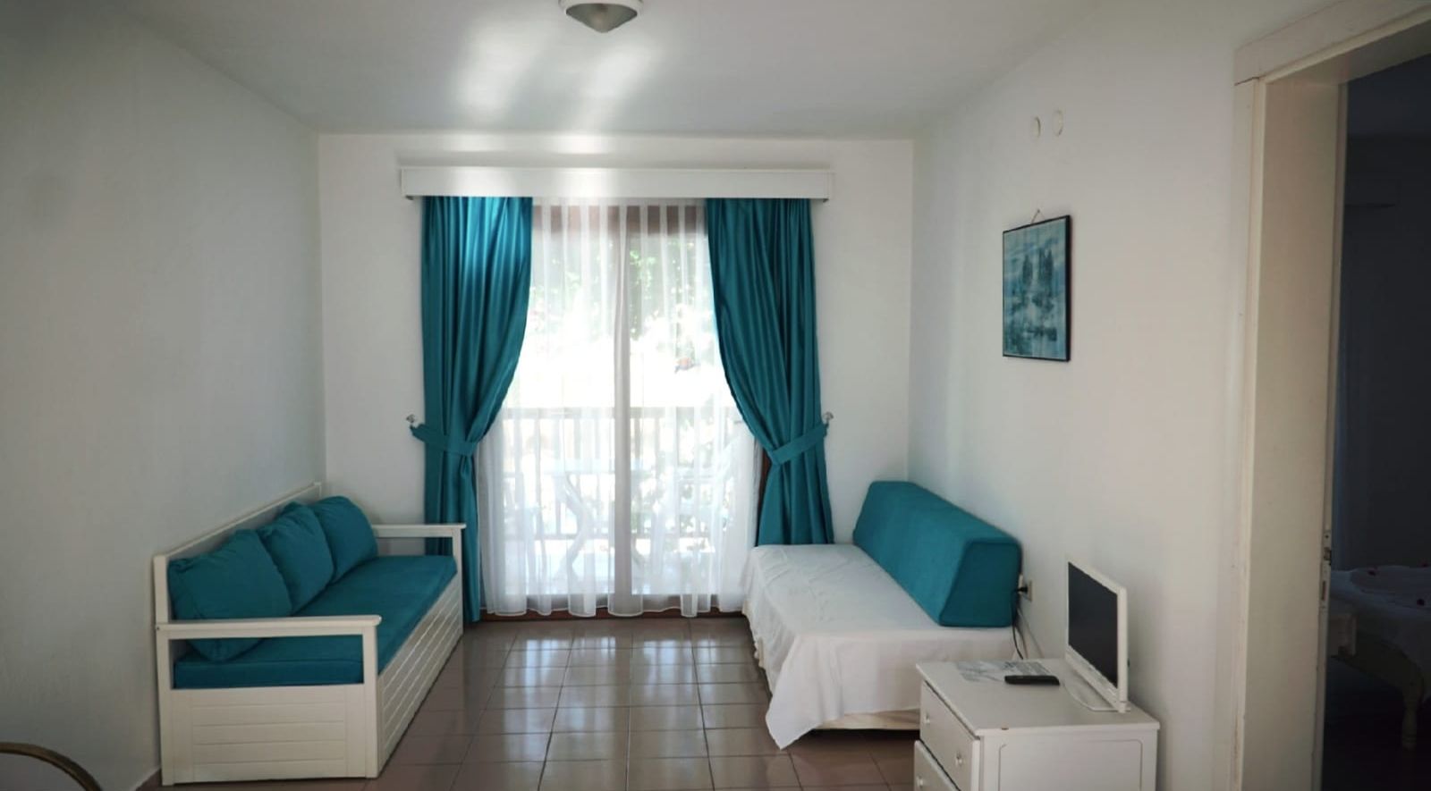Una habitación con una cama, un escritorio con ordenador y un sofá.