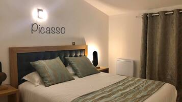 A bedroom with a bed, a nightstand, a wall-mounted light, a thermostat, and a curtain.