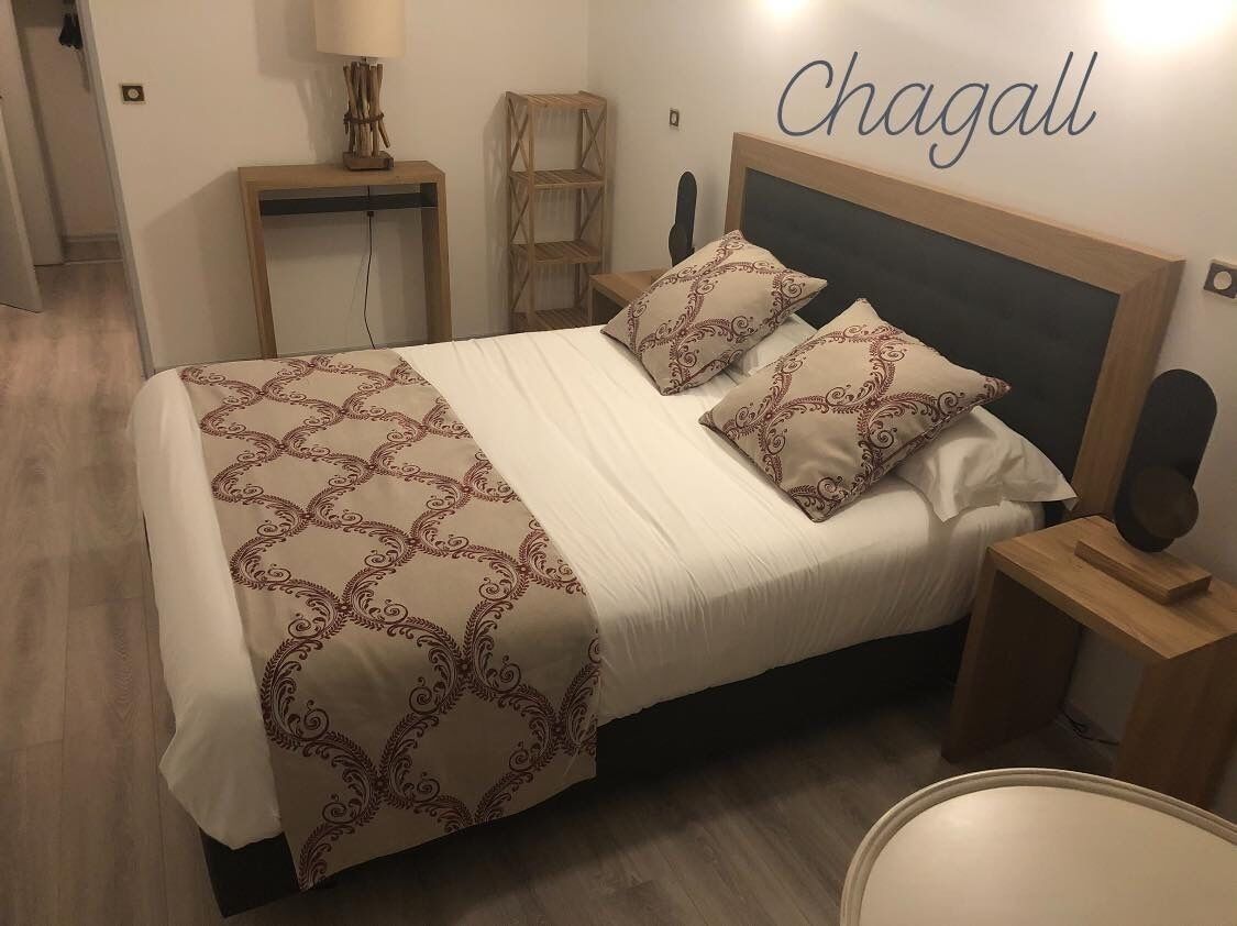 A neatly made bed with patterned bedding, a bedside table with a lamp, and a wall-mounted shelf.